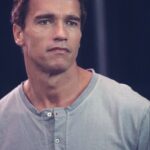 A robust portrait of actor and former governor Arnold Schwarzenegger, with a confident, friendly expression in a casual blazer.