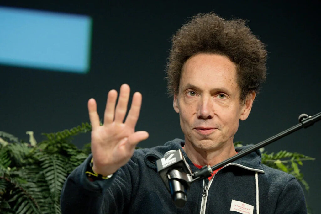 Author Malcolm Gladwell gesturing during a media interview or podcast recording.
