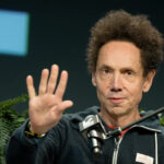 Author Malcolm Gladwell gesturing during a media interview or podcast recording.
