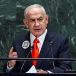 A formal political portrait of Israeli Prime Minister Benjamin Netanyahu, speaking behind a podium at an official event.