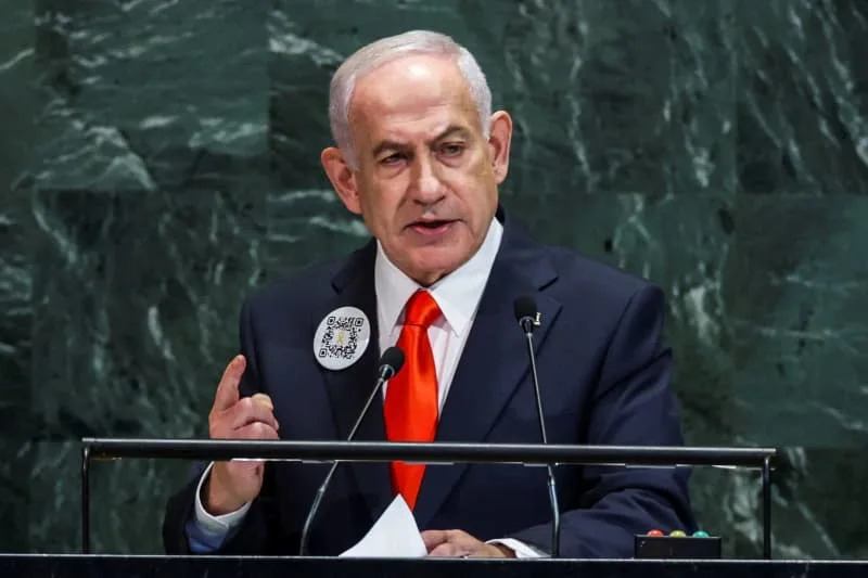 A formal political portrait of Israeli Prime Minister Benjamin Netanyahu, speaking behind a podium at an official event.