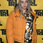 Billie Eilish posing for a portrait in an oversized outfit.
