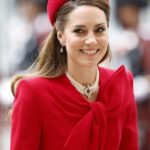 A poised portrait of Catherine, Princess of Wales, smiling warmly with styled brown hair, wearing an elegant, brightly colored tailored dress.