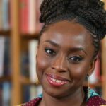 Headshot of author Chimamanda Ngozi Adichie looking directly into the camera with a warm, radiant smile.