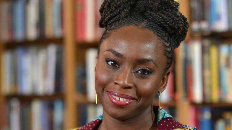Headshot of author Chimamanda Ngozi Adichie looking directly into the camera with a warm, radiant smile.