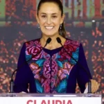 Claudia Sheinbaum, President of Mexico, smiling in a formal dress while standing at a podium.