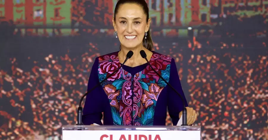 Claudia Sheinbaum, President of Mexico, smiling in a formal dress while standing at a podium.