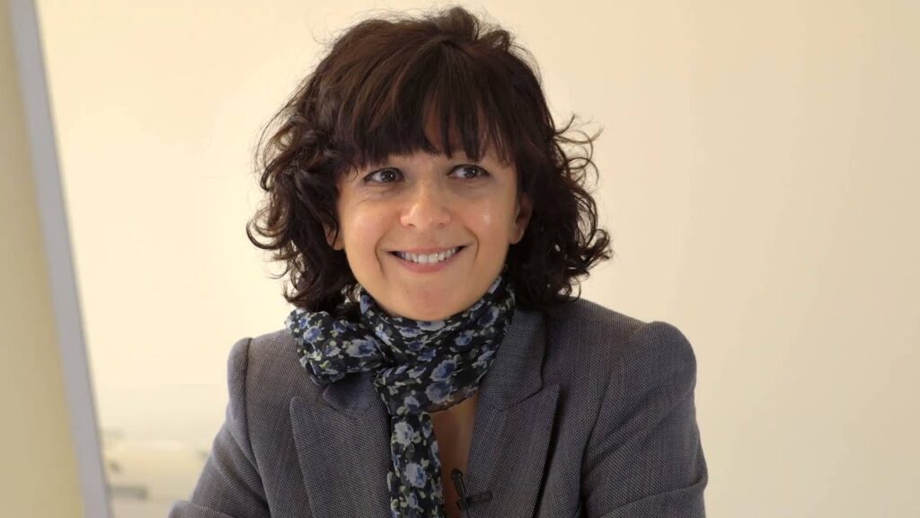 Dr. Emmanuelle Charpentier smiling warmly during a science keynote presentation.