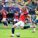 Erling Haaland striking a soccer ball mid-match.