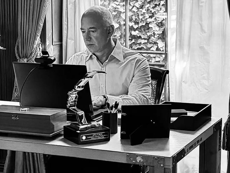 Black and white portrait of young Jeff Bezos in 1994 working at a desk with an early computer in his Bellevue garage setup.