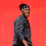 A charismatic portrait of YouTuber and boxer KSI, wearing his signature bandana and styled athletic wear, smiling at the camera.