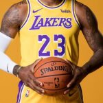 A powerful portrait of basketball player LeBron James in his team jersey, holding a basketball with a focused expression.