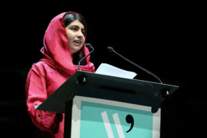 Activist Malala Yousafzai addressing an audience from a podium at a global event.