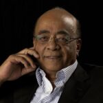 A professional headshot of Sudanese-British billionaire and philanthropist Mo Ibrahim, wearing glasses and a smart-casual suit jacket.