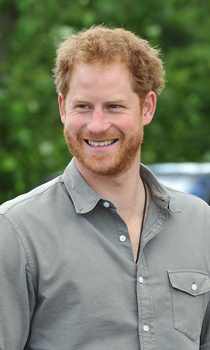 A friendly, close-up portrait of Prince Harry, the Duke of Sussex, smiling with his signature red beard and hair, wearing a smart-casual shirt.