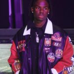 A youthful, edgy portrait of Nigerian musician Rema, styled in contemporary streetwear, showcasing his unique fashion-forward aesthetic.