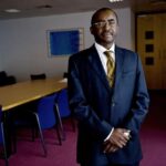 A professional portrait of Zimbabwean businessman and philanthropist Strive Masiyiwa, wearing glasses and a formal dark suit.