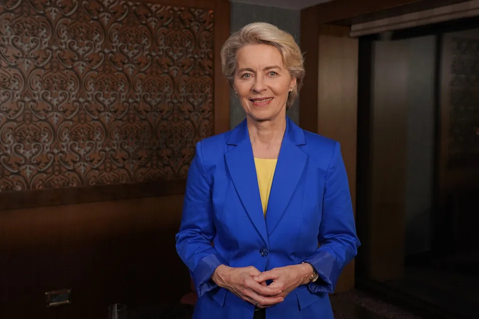 Ursula von der Leyen, President of the European Commission, wearing a blue suit and smiling in a neutral background.