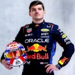 A professional portrait of Formula 1 driver Max Verstappen wearing his team racing suit and holding his helmet.