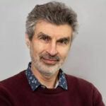 Yoshua Bengio, computer scientist and AI pioneer, smiling in front of a neutral background.